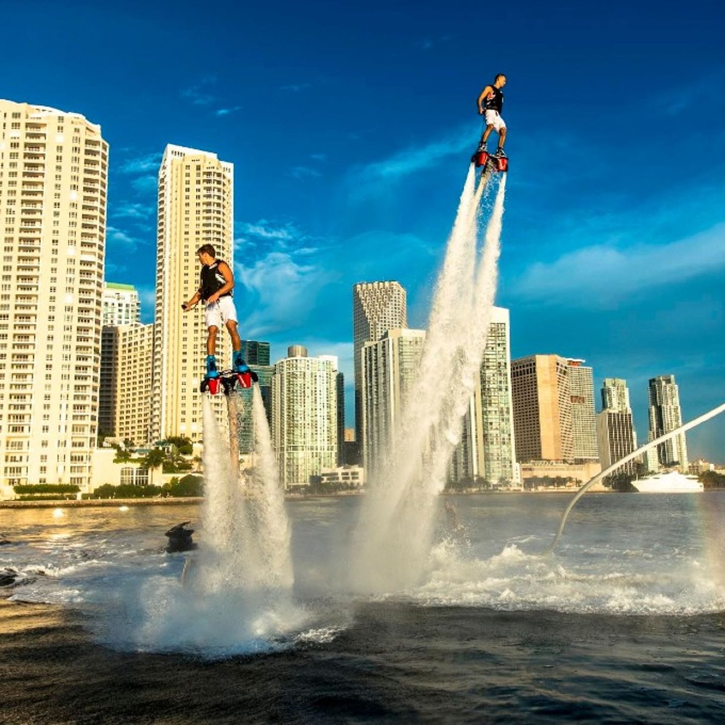 Two people flyboarding near city