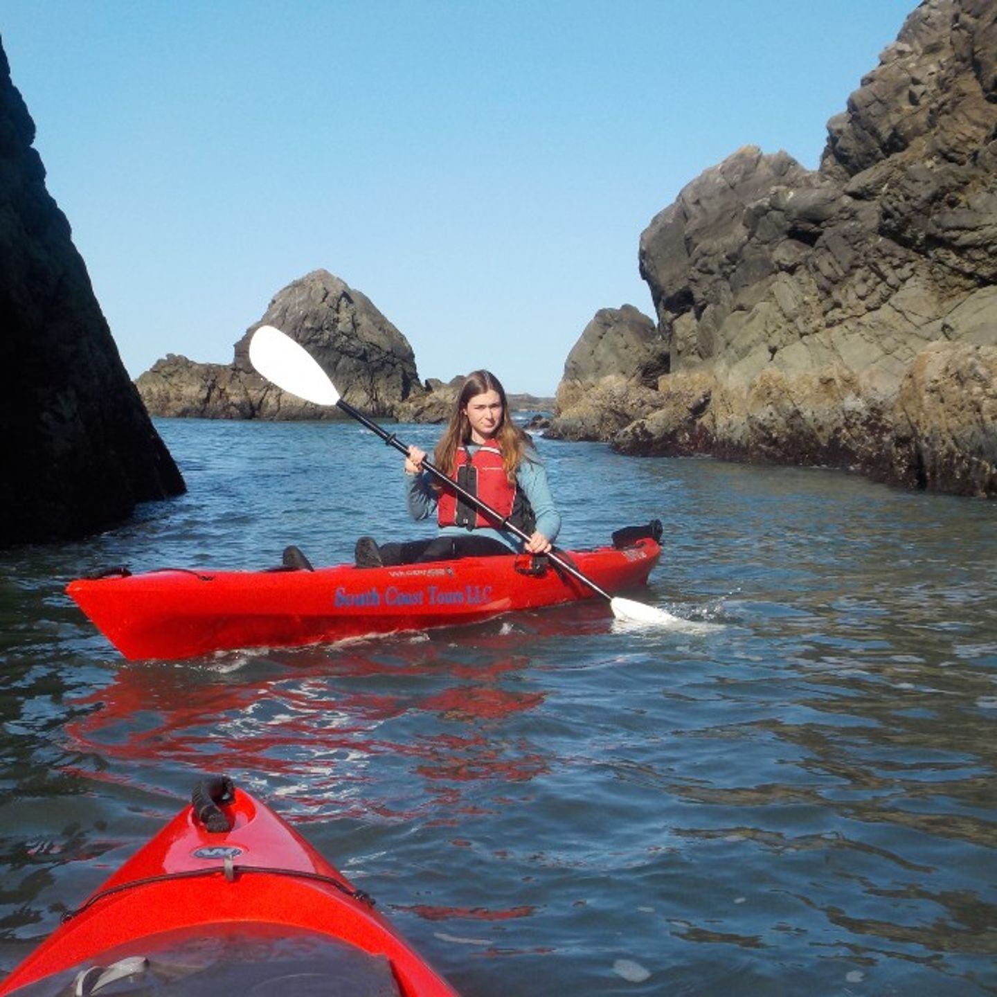 Girl kayaking near rocks