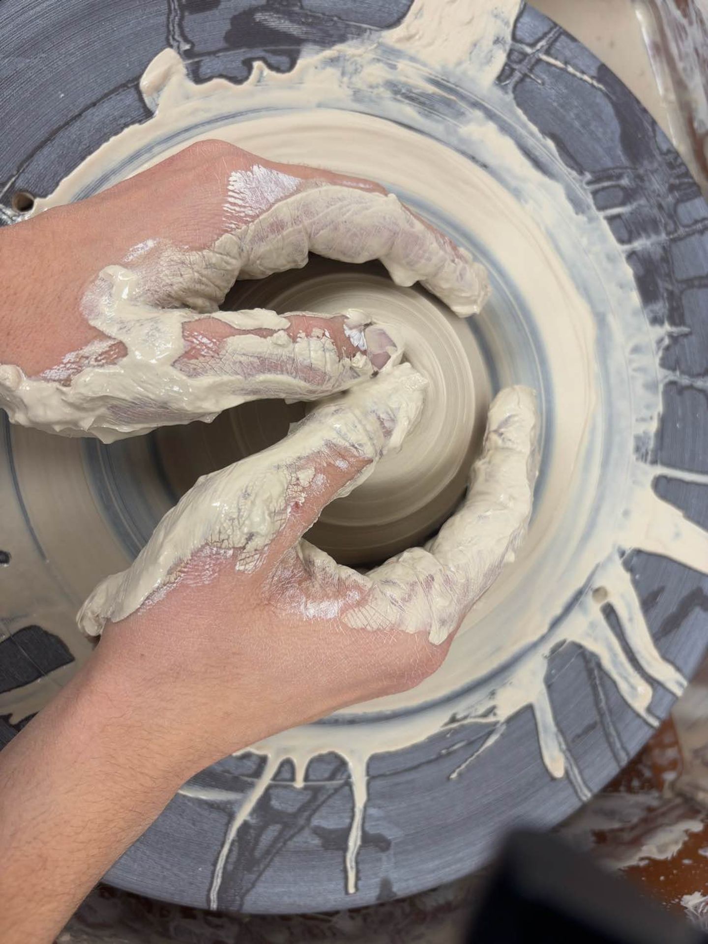 Hands making a pot on the wheel