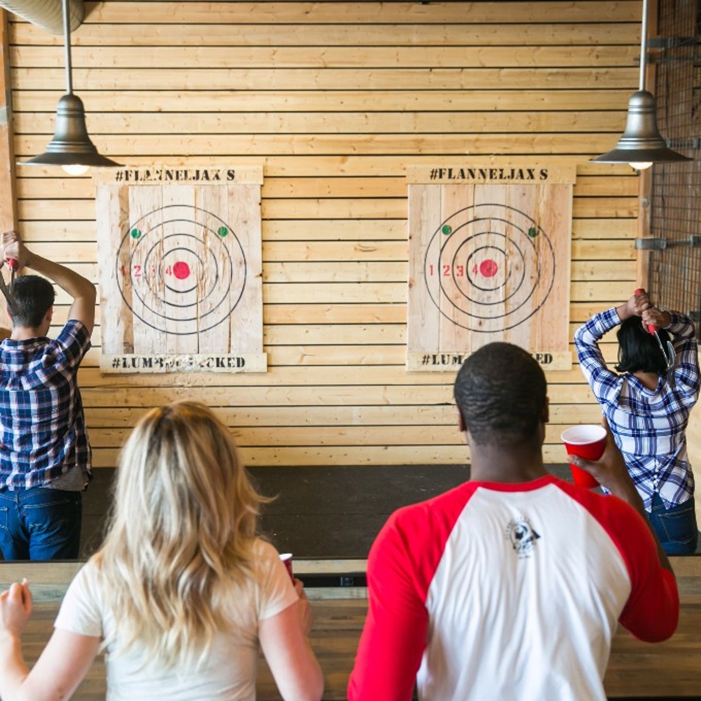 Two People Watching Others Throw Axes