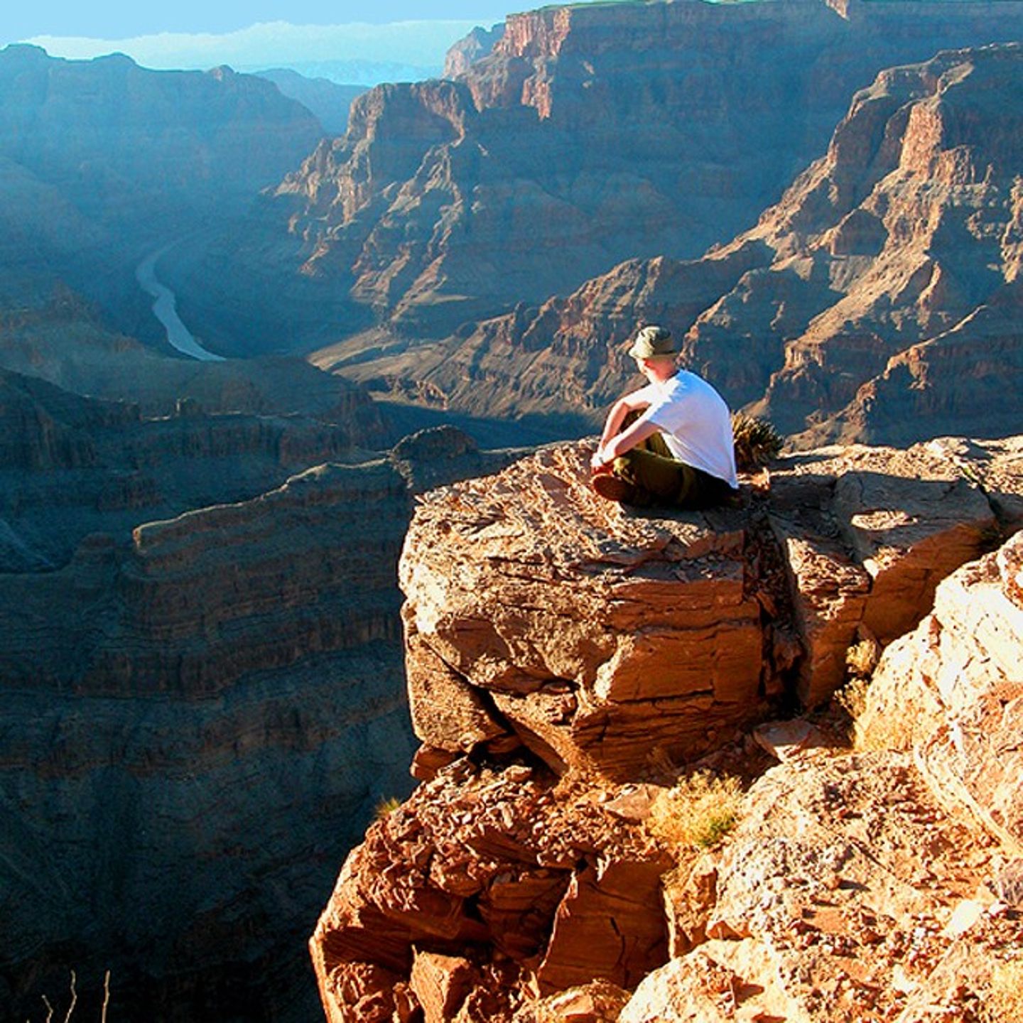 Person sitting on rock over canyon