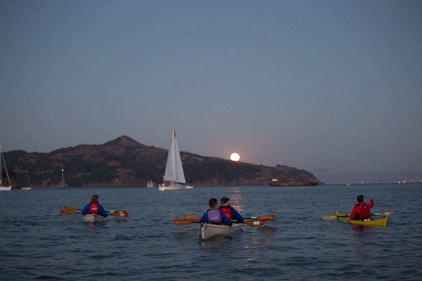 Group kayaking under moon