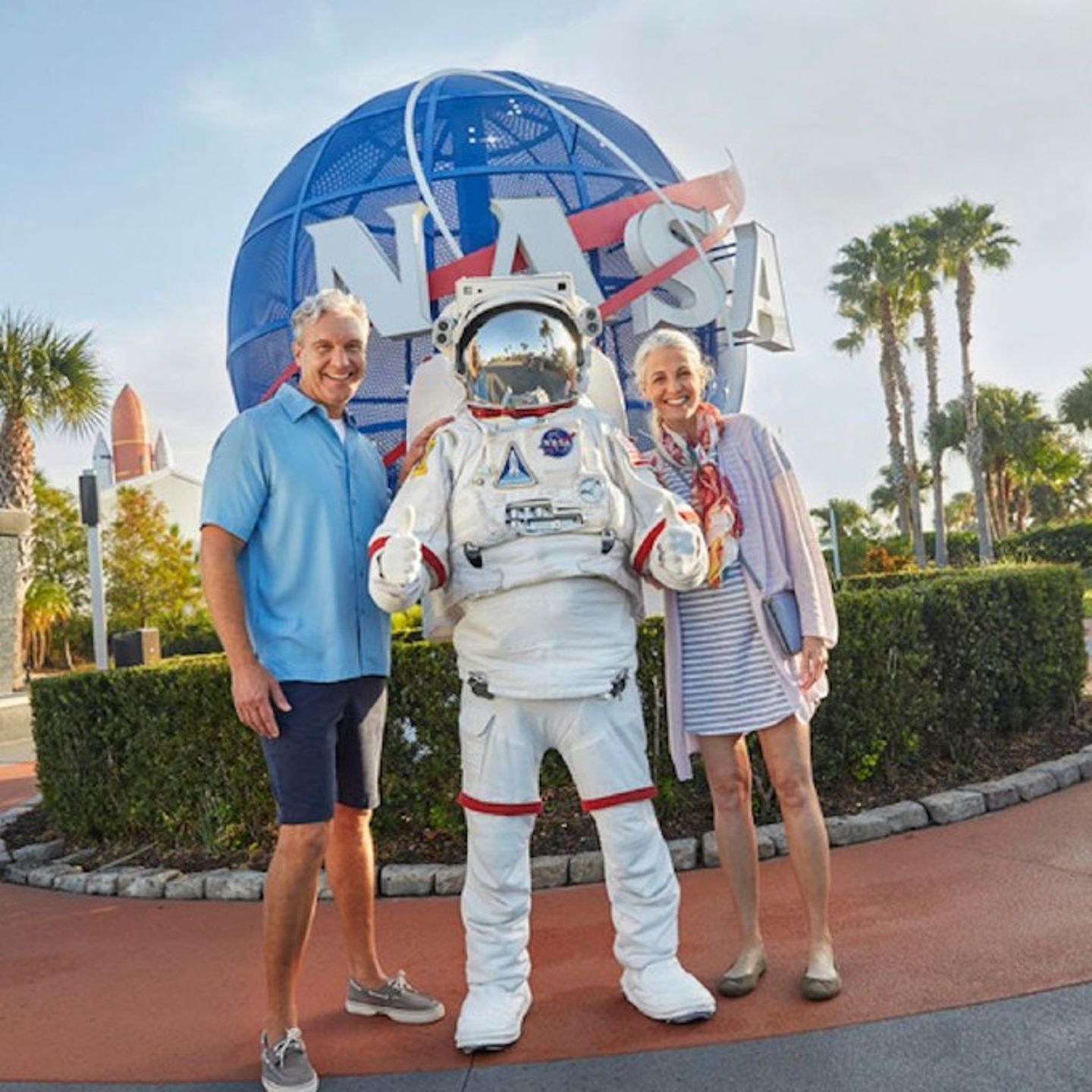 Two people posing with astronaut statue