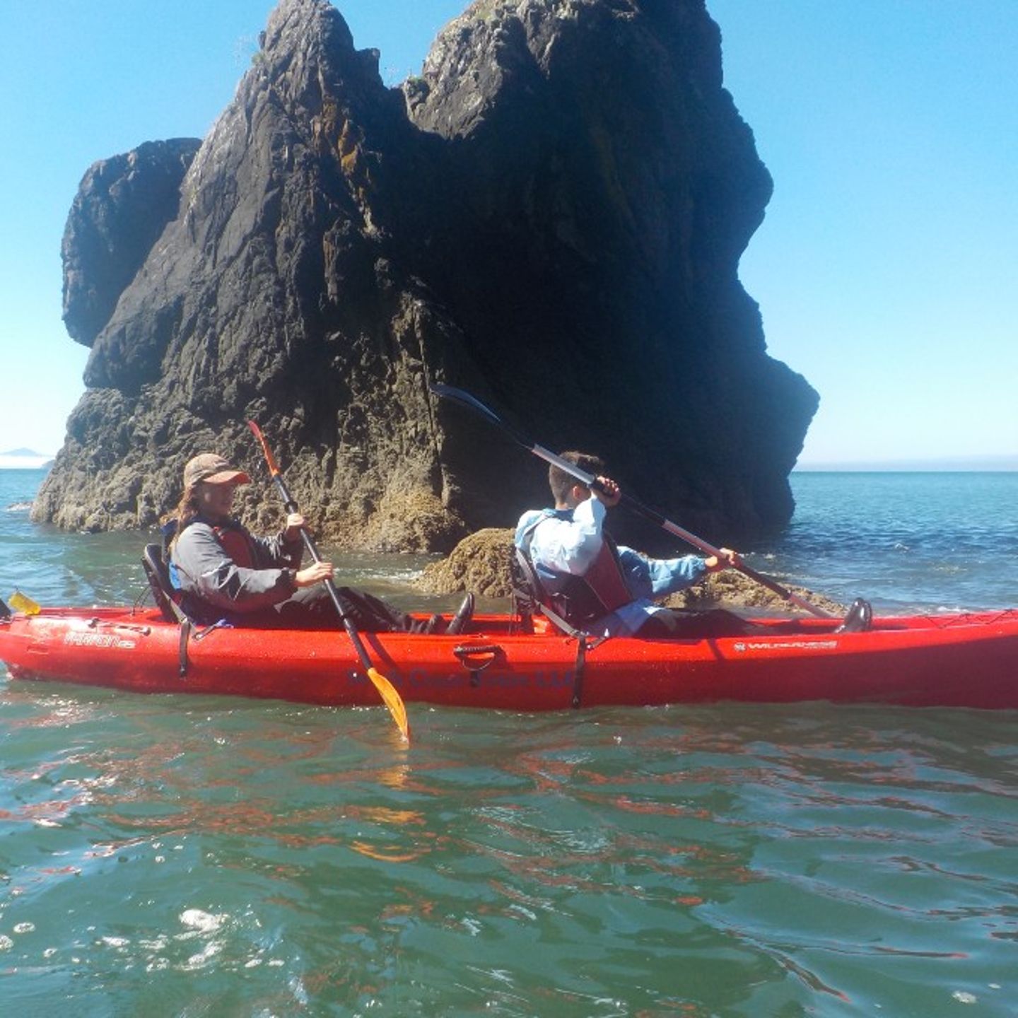 Two people in kayak in front of rock