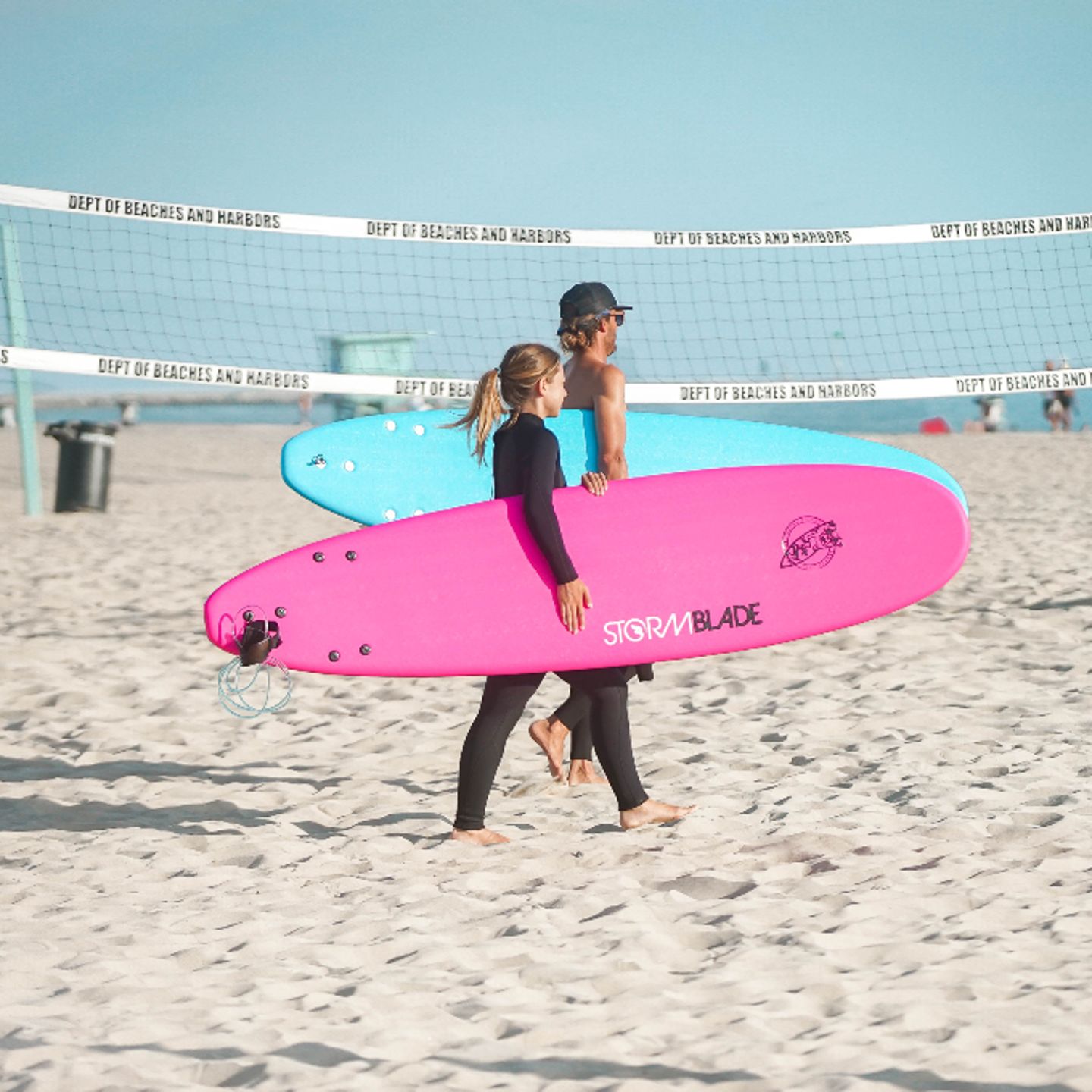 Two people walking with surf boards