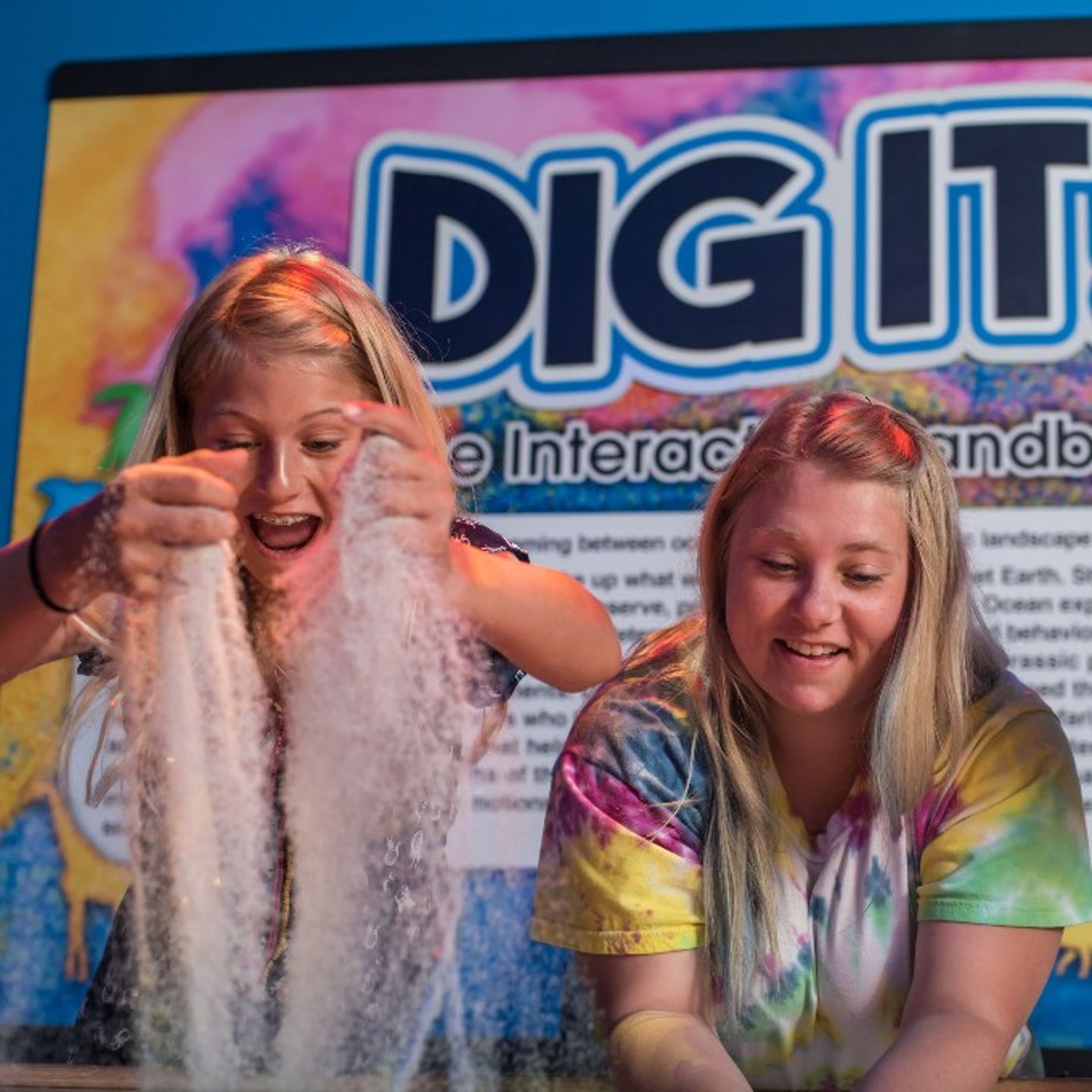 Two girls digging in sand